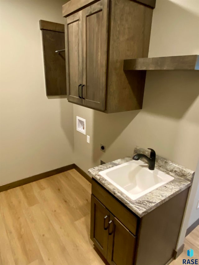 laundry area with hookup for a washing machine, cabinets, sink, electric dryer hookup, and light wood-type flooring