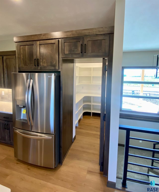 kitchen with backsplash, light hardwood / wood-style floors, dark brown cabinetry, and stainless steel refrigerator with ice dispenser