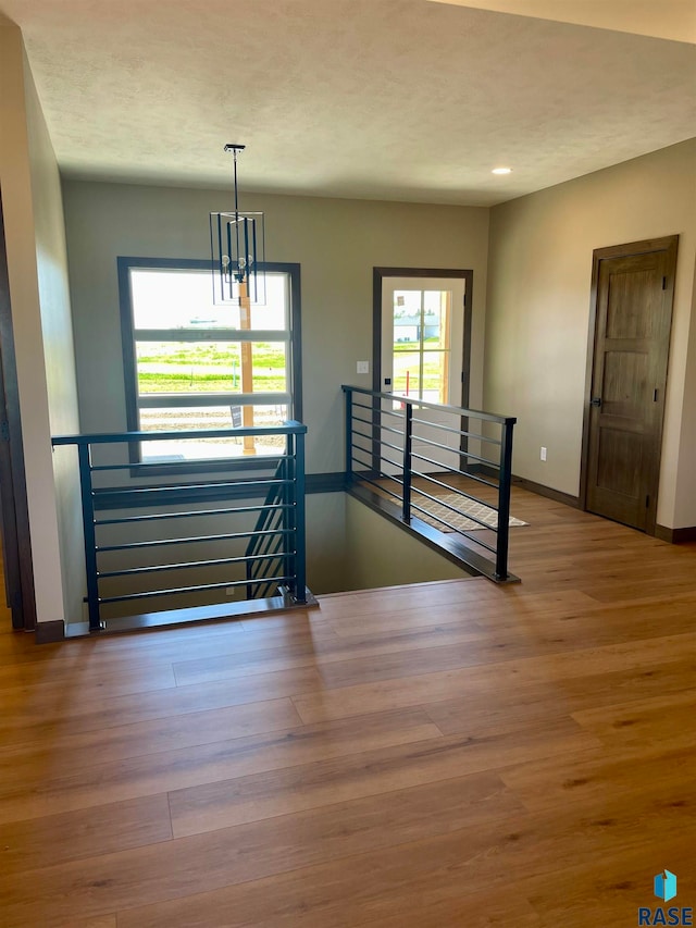 stairway featuring hardwood / wood-style flooring, an inviting chandelier, and a textured ceiling