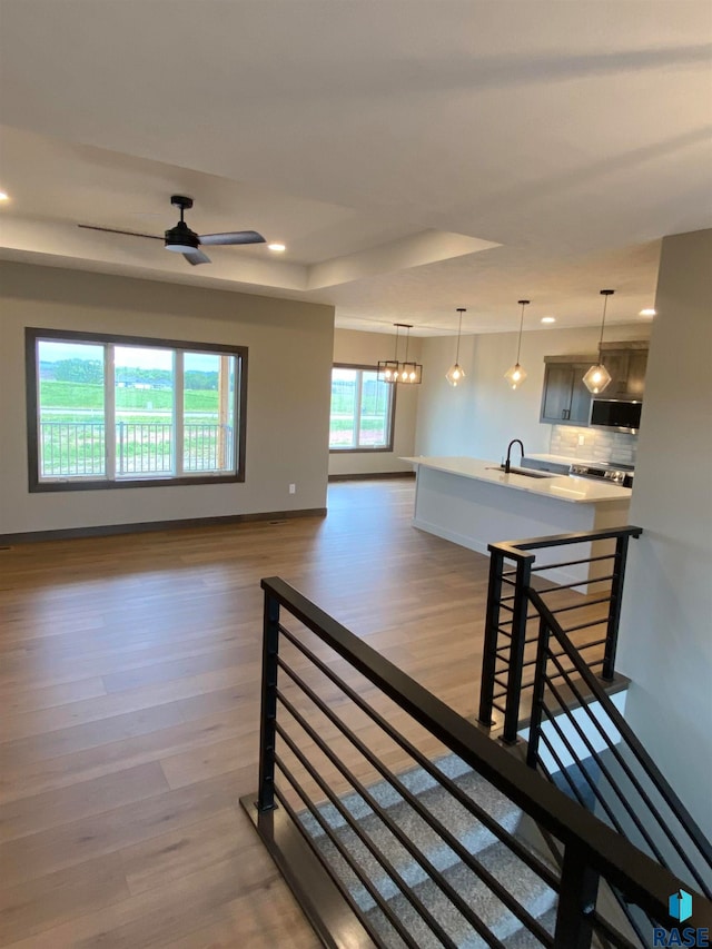 interior space with ceiling fan with notable chandelier, a wealth of natural light, dark hardwood / wood-style flooring, and sink