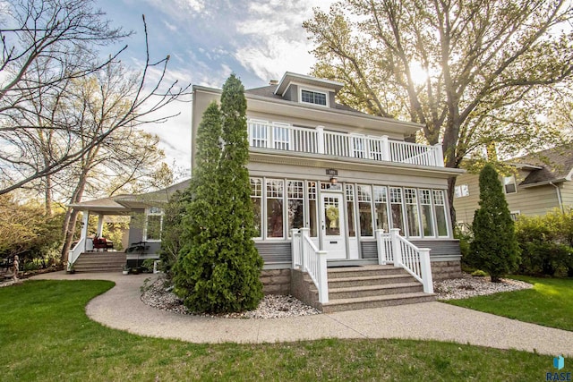 view of front of home featuring a balcony and a front yard