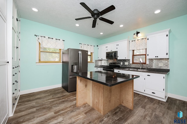 kitchen featuring dark countertops, stainless steel fridge, tasteful backsplash, and black range with electric stovetop