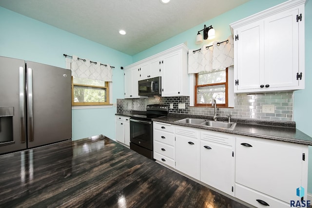 kitchen with black appliances, white cabinets, dark countertops, and a sink