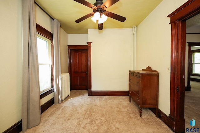 carpeted bedroom with baseboards, multiple windows, radiator, and ceiling fan