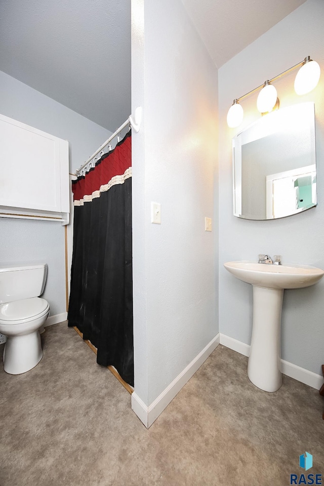 bathroom with curtained shower, toilet, and baseboards