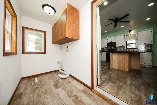 laundry area featuring a sink, wood finished floors, baseboards, ceiling fan, and laundry area