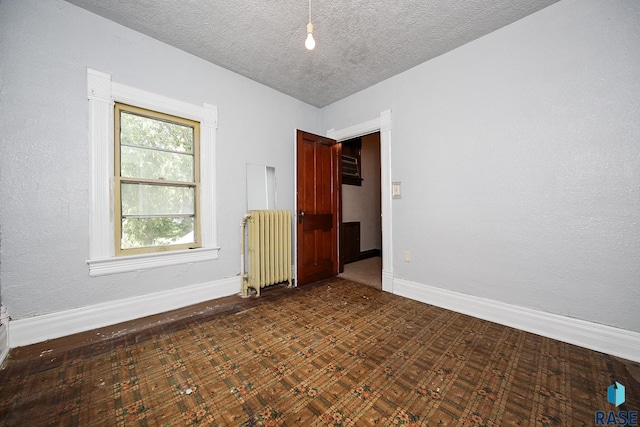 unfurnished room featuring baseboards, radiator, and a textured ceiling