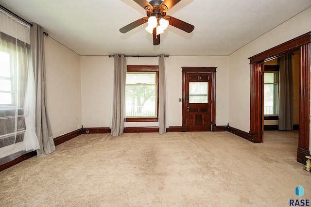 empty room featuring baseboards, light colored carpet, and ceiling fan