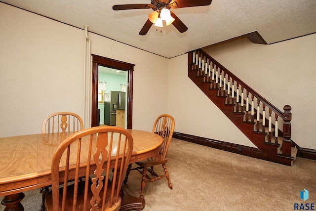 dining room with a ceiling fan, carpet, baseboards, stairs, and a textured ceiling