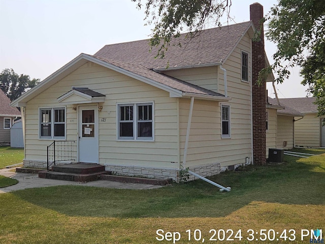 view of front of home with central AC unit and a front lawn