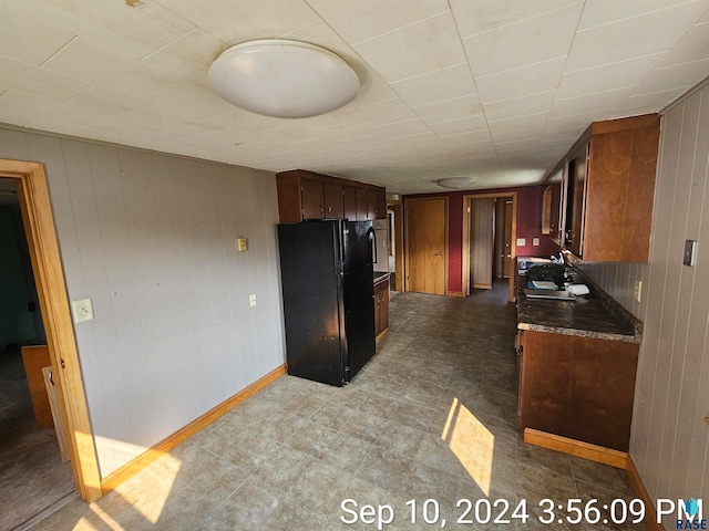 kitchen featuring wood walls and black fridge