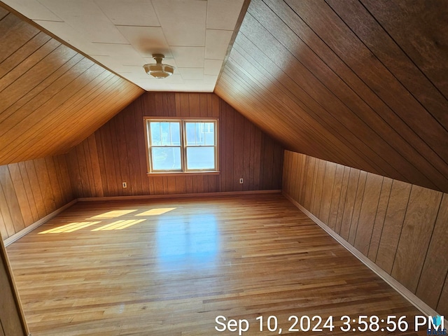 additional living space featuring vaulted ceiling, hardwood / wood-style floors, and wooden walls