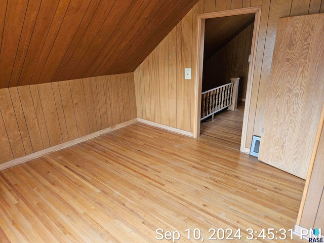 bonus room with lofted ceiling, wood walls, wooden ceiling, and light hardwood / wood-style floors