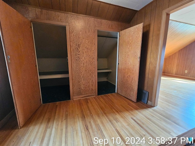 unfurnished bedroom with wood walls, vaulted ceiling, light hardwood / wood-style floors, and wooden ceiling