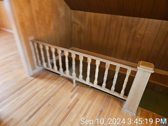 stairway with hardwood / wood-style floors and wood walls