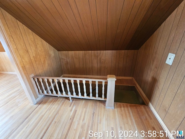 interior space with hardwood / wood-style floors, vaulted ceiling, wooden walls, and wooden ceiling