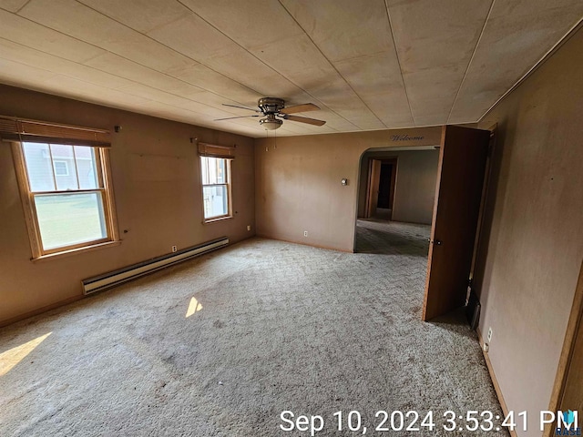 carpeted spare room with a baseboard heating unit and ceiling fan