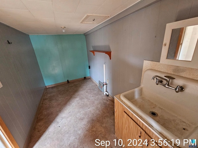 bathroom with concrete floors, sink, and wooden walls