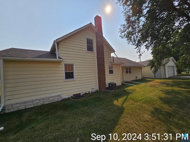 view of property exterior featuring an outbuilding, a yard, a garage, and central AC unit