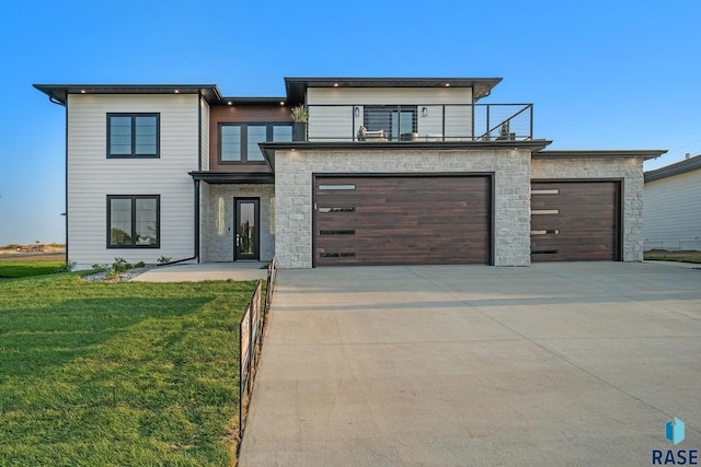 contemporary home with a front yard, a garage, and a balcony