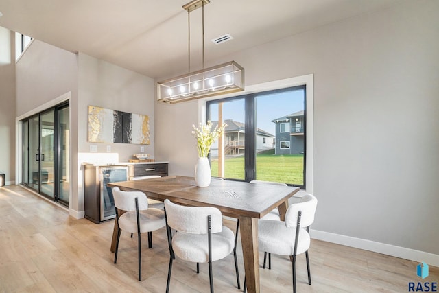 dining room with beverage cooler and light hardwood / wood-style flooring