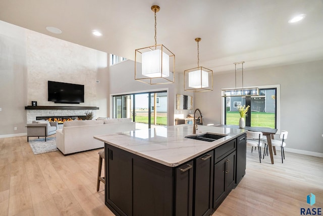 kitchen featuring light stone counters, light hardwood / wood-style floors, a fireplace, and sink