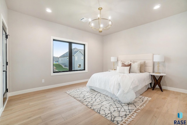 bedroom with a chandelier and light hardwood / wood-style floors