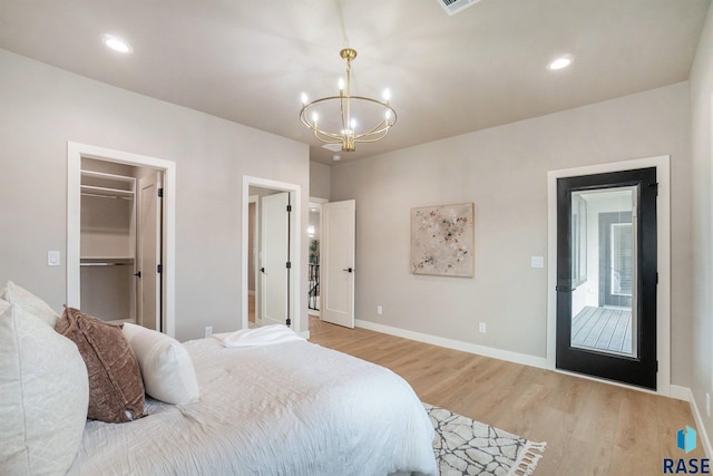 bedroom featuring an inviting chandelier, light hardwood / wood-style floors, a spacious closet, and a closet