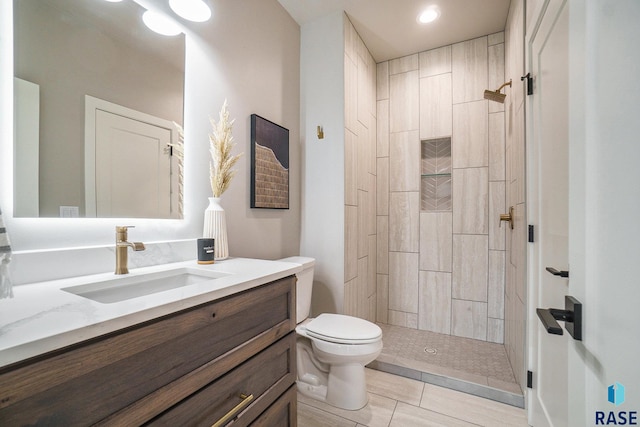 bathroom featuring tiled shower, vanity, toilet, and tile patterned flooring