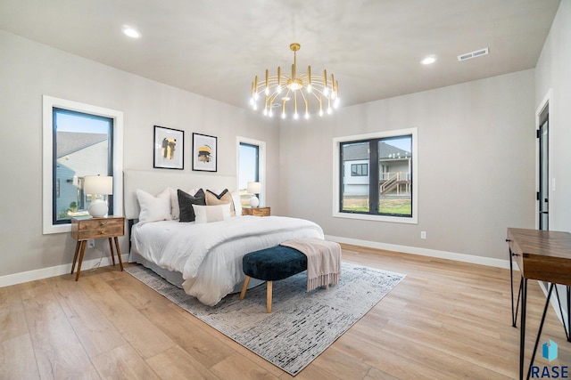 bedroom featuring a notable chandelier, light wood-type flooring, and multiple windows