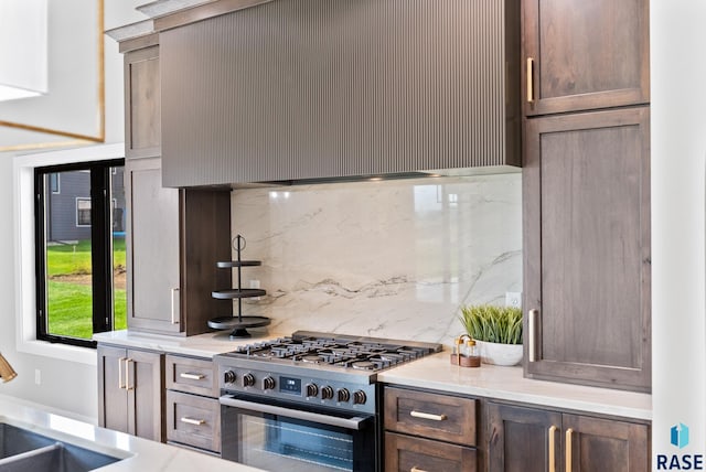 kitchen featuring high end stove, backsplash, and dark brown cabinetry