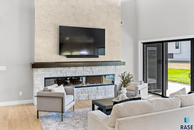 living room with a towering ceiling, light hardwood / wood-style floors, and a fireplace