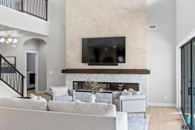 living room featuring a high ceiling, light wood-type flooring, and a fireplace