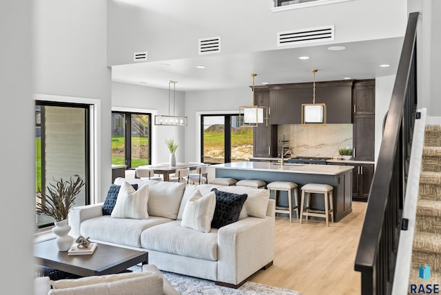 living room featuring a high ceiling, light hardwood / wood-style floors, and sink