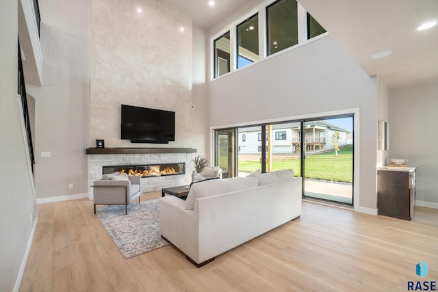 living room featuring a high ceiling, light hardwood / wood-style floors, and a fireplace