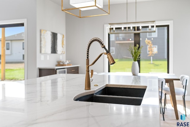 kitchen with light stone countertops, sink, and decorative light fixtures