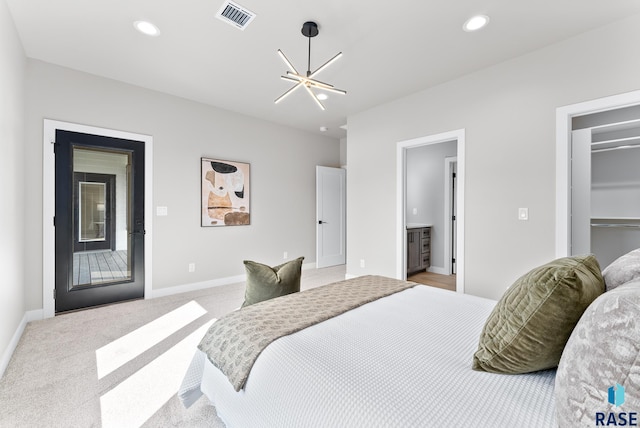 carpeted bedroom featuring an inviting chandelier, a closet, ensuite bath, and access to exterior