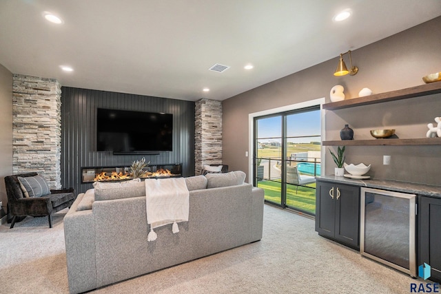 carpeted living room featuring a stone fireplace and bar