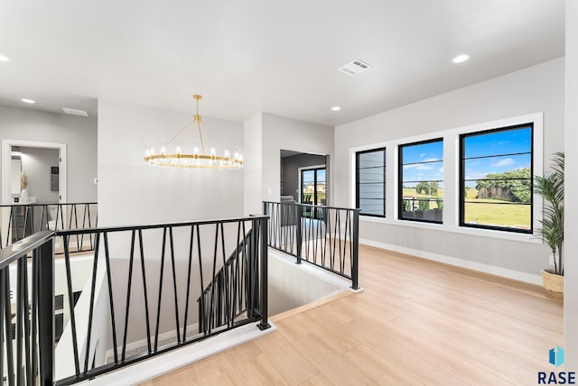 corridor with light hardwood / wood-style floors and an inviting chandelier