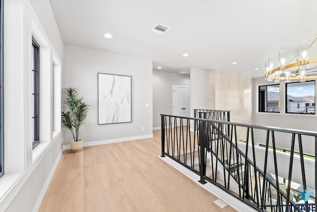 hall featuring light wood-type flooring and a chandelier