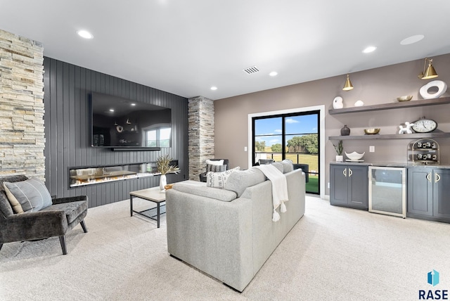 carpeted living room featuring a stone fireplace and wine cooler