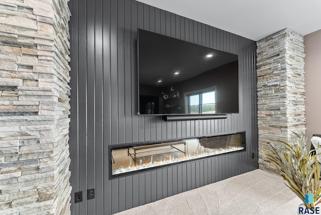 interior space with a stone fireplace, wooden walls, and carpet flooring