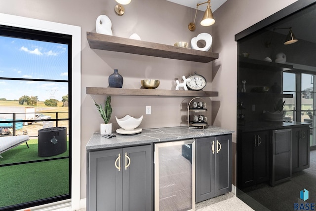 bar featuring beverage cooler, pendant lighting, and gray cabinets