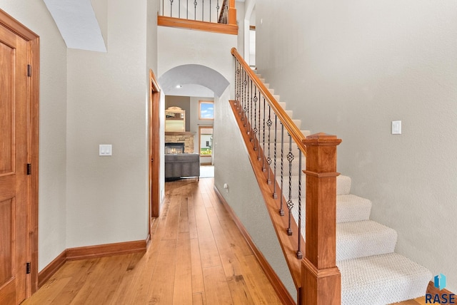 staircase featuring a high ceiling, hardwood / wood-style flooring, and a fireplace