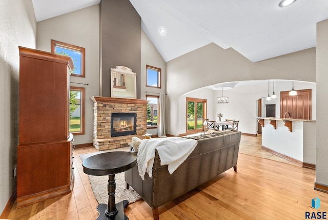 living room with high vaulted ceiling, a fireplace, light hardwood / wood-style floors, and a healthy amount of sunlight