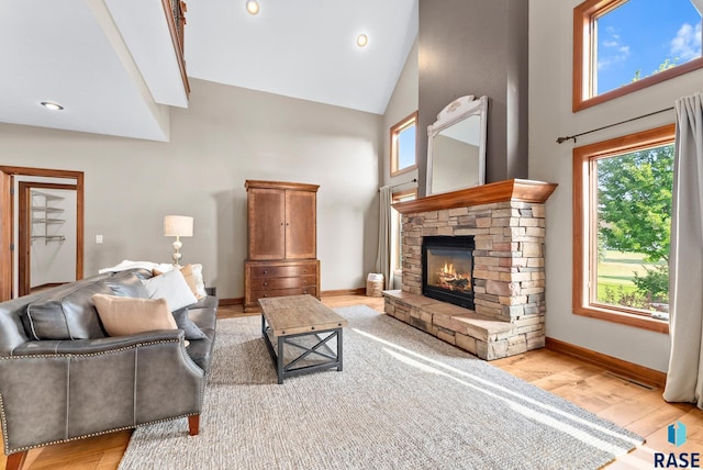 living room featuring a fireplace, high vaulted ceiling, a wealth of natural light, and light hardwood / wood-style flooring