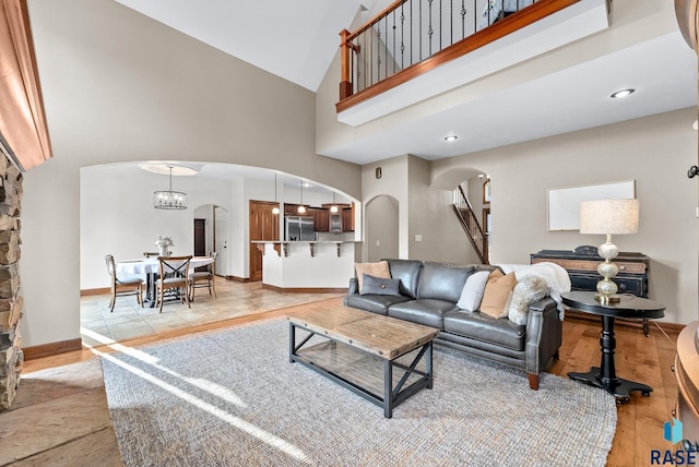 living room with light hardwood / wood-style flooring, high vaulted ceiling, and a chandelier