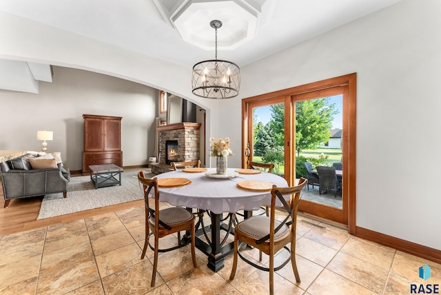 dining room with a chandelier and a stone fireplace