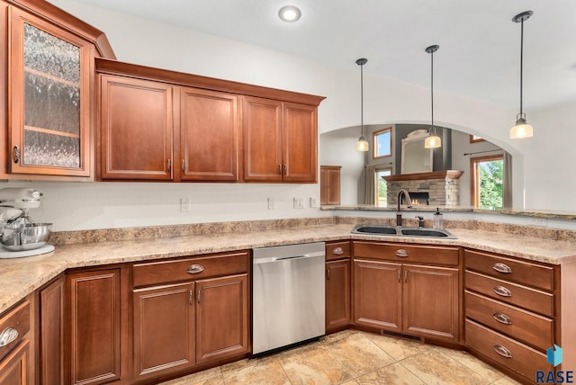 kitchen featuring decorative light fixtures, a stone fireplace, sink, and stainless steel dishwasher