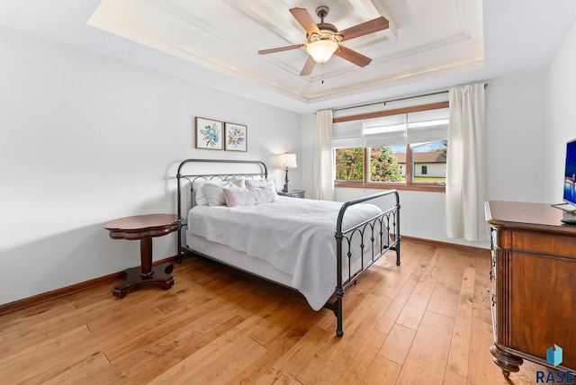 bedroom featuring a tray ceiling, ceiling fan, and light hardwood / wood-style flooring